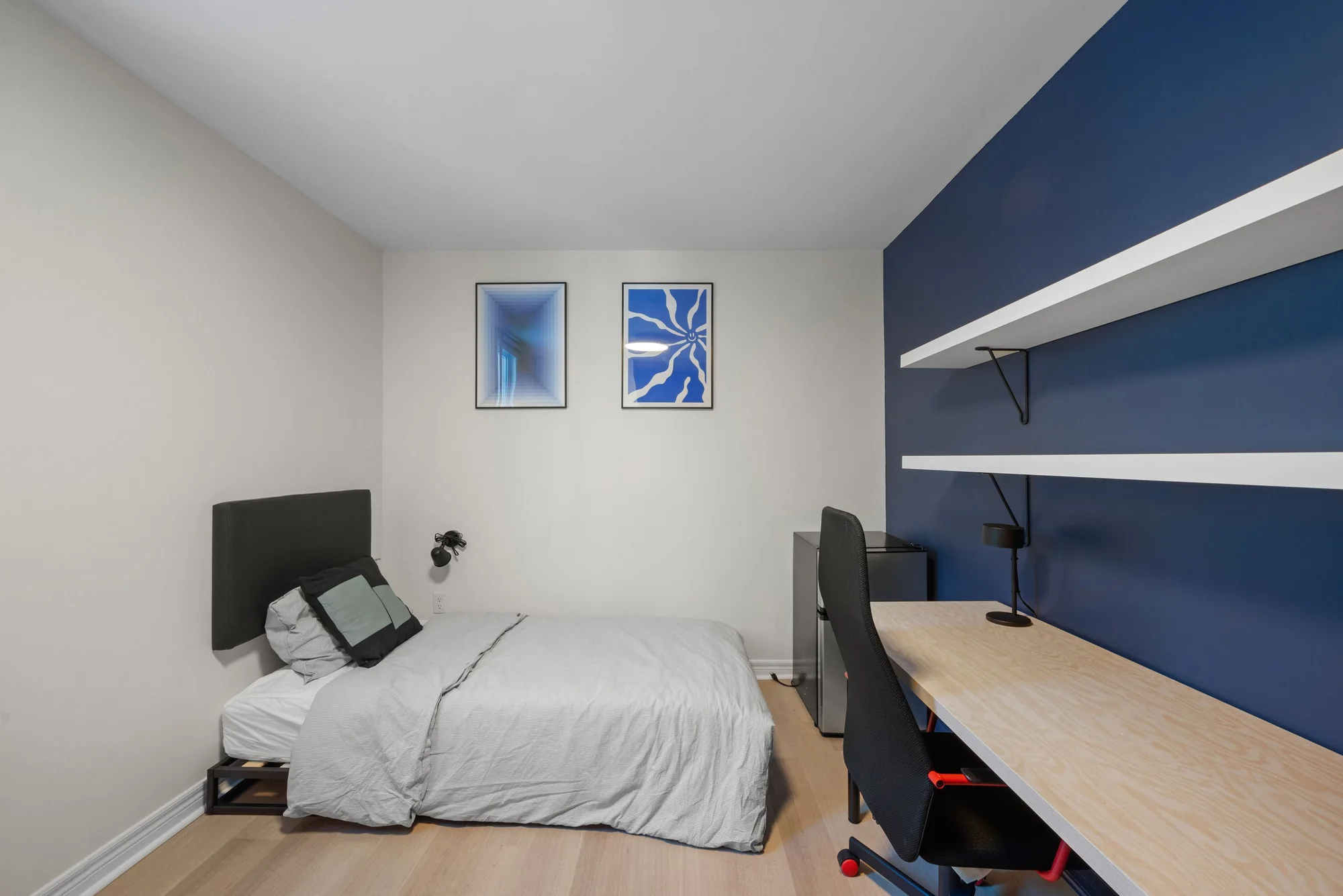 Room example with a blue feature wall, bed, and study desk